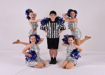 Cheerleaders posing with a referee.