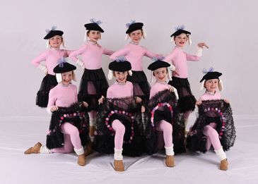 Young girls in pink and black dance costumes posing.