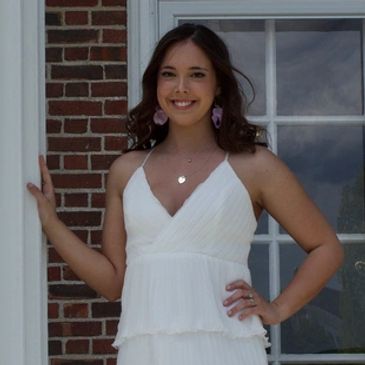 Young woman smiling in a white dress.
