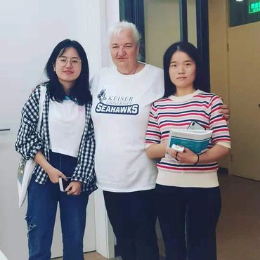 Three women standing closely together, two holding books and phones.