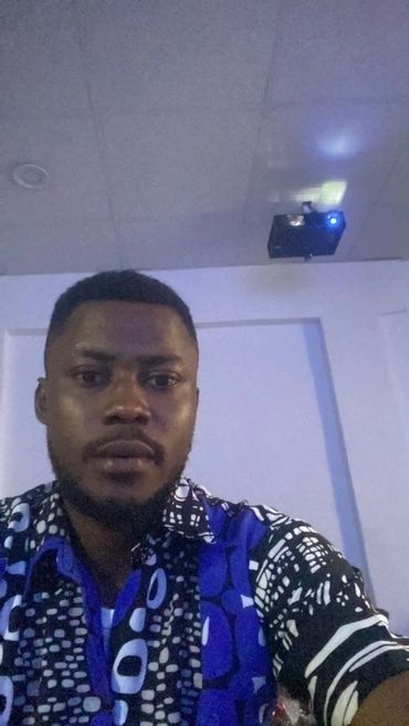 Man wearing a patterned blue and black shirt indoors.
