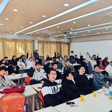 A lively classroom with students raising their hands and engaging actively.