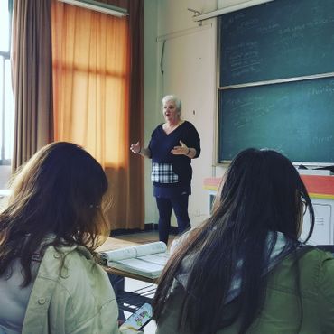 A teacher giving a lesson while students take notes in a classroom.