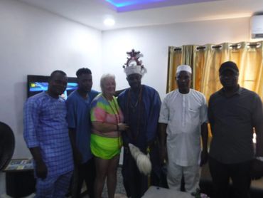 Group photo of six people indoors, including a woman and men in traditional and casual attire.