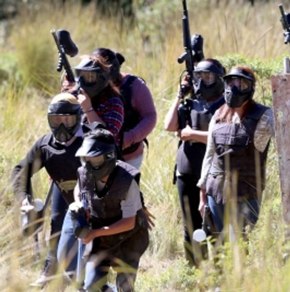 Grupo de personas jugando paintball al aire libre.
