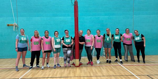 Group of women standing in a sports hall for netball.