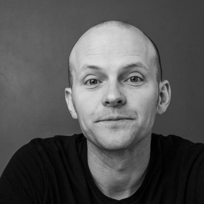 Black and white portrait of a bald man with a subtle smile.