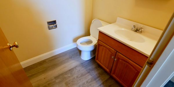 Small bathroom with wooden vanity and toilet.