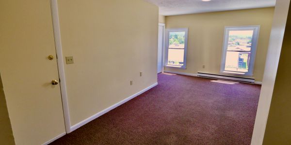 Empty room with beige walls and brown carpet.