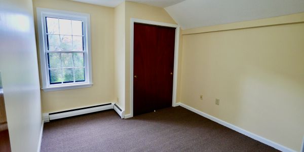 Empty room with beige walls and a closed wooden closet.