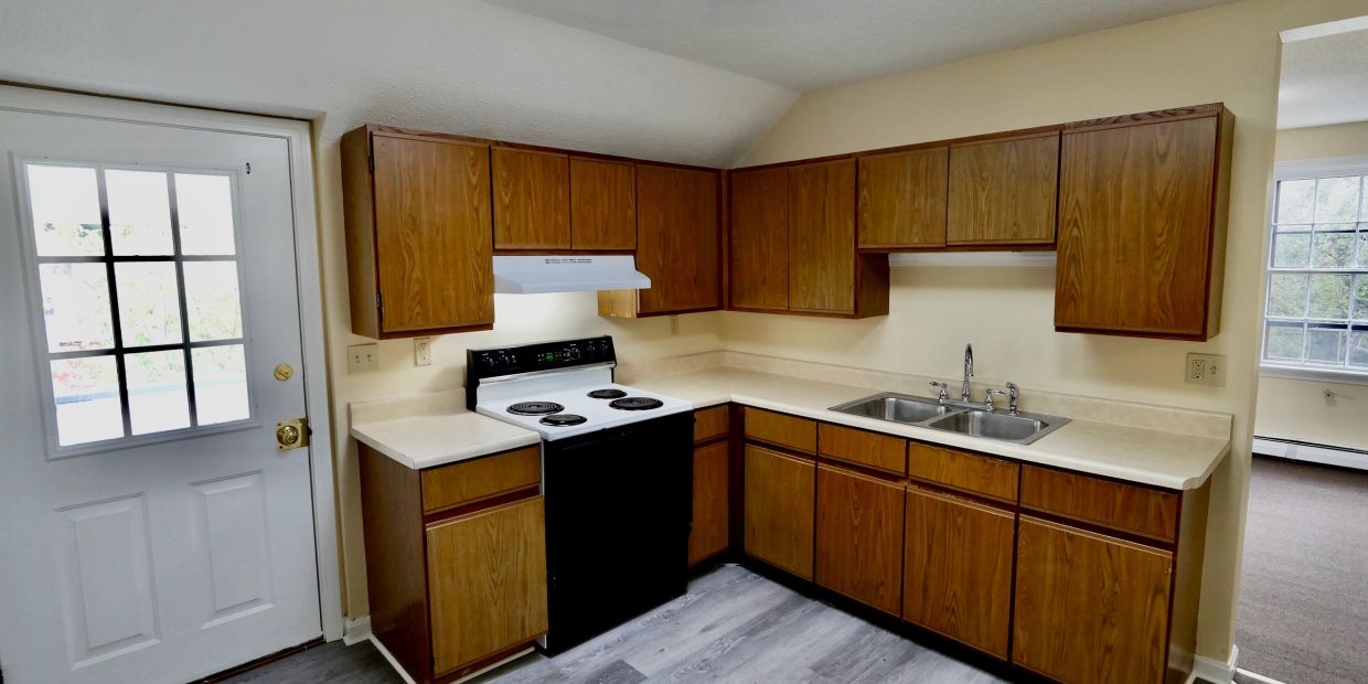 Clean kitchen with wooden cabinets and white appliances.
