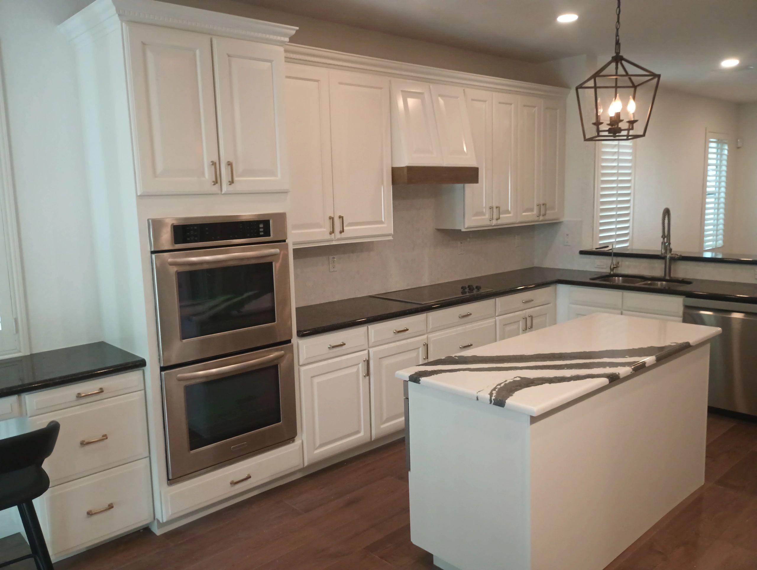Modern kitchen with white cabinets, black countertops, and striped island.