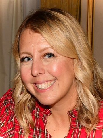 Smiling woman with blonde hair wearing a red plaid shirt.