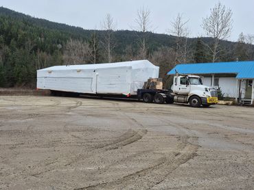 16' wide oversize modular home on trailer behind transport truck.