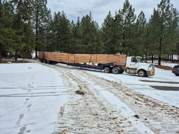 Transport truck and step-deck expando trailer loaded with 85' trusses