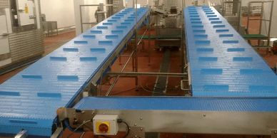 straight modular belt conveyor feeding two modular flighted belt conveyor systems for meat packagingo