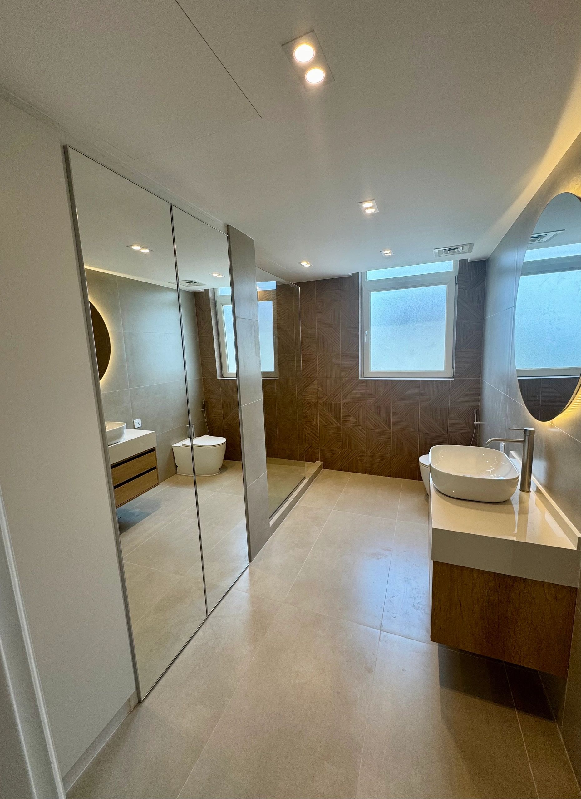 Modern bathroom with large mirror and elegant fixtures.