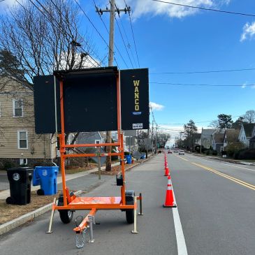 Roadside LED sign and traffic cones on a residential street.