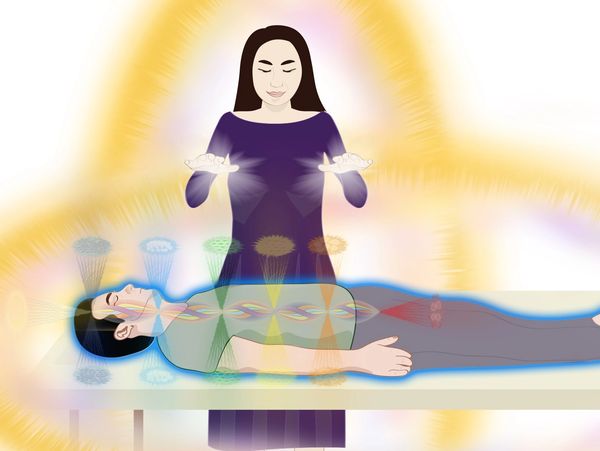 Woman giving energy healing to client laying on a table.  