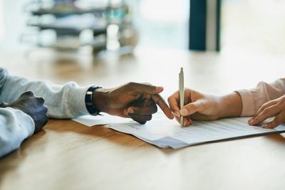 Photo of prepared legal document being signed between a man and a woman. Photo only shows their arms