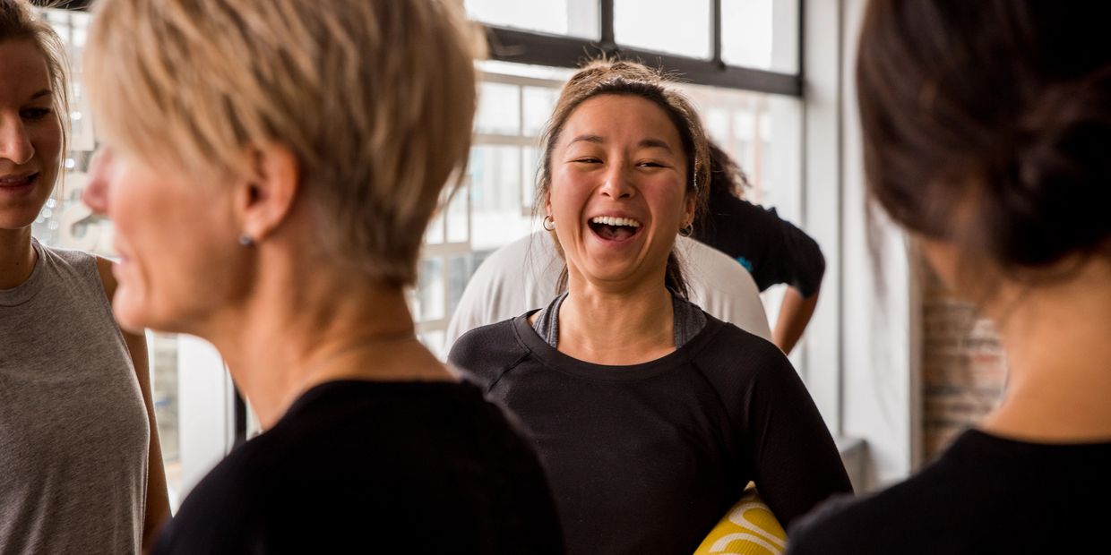 Femme riant pendant cours de yoga en entreprise | Équilibre