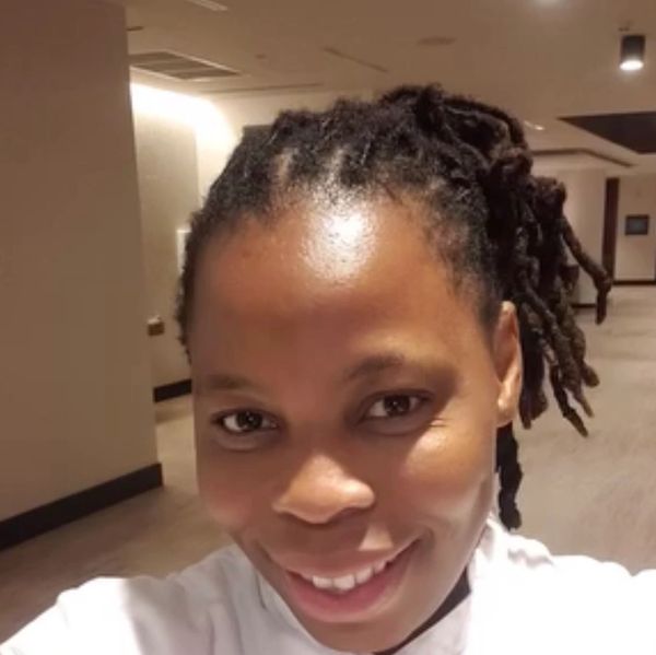 Woman with braided hair smiling indoors.