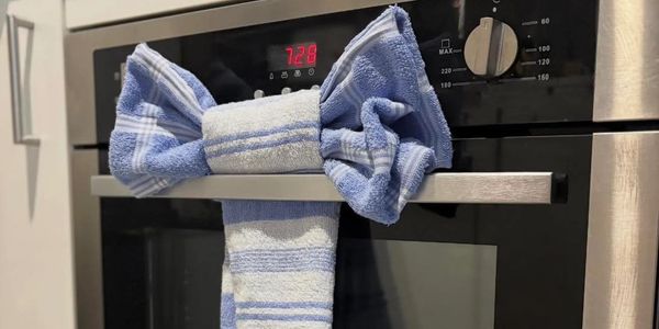 Blue and white towel shaped like a bow on an oven handle.
