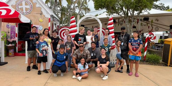A diverse group of people posing outdoors with candy cane decorations.