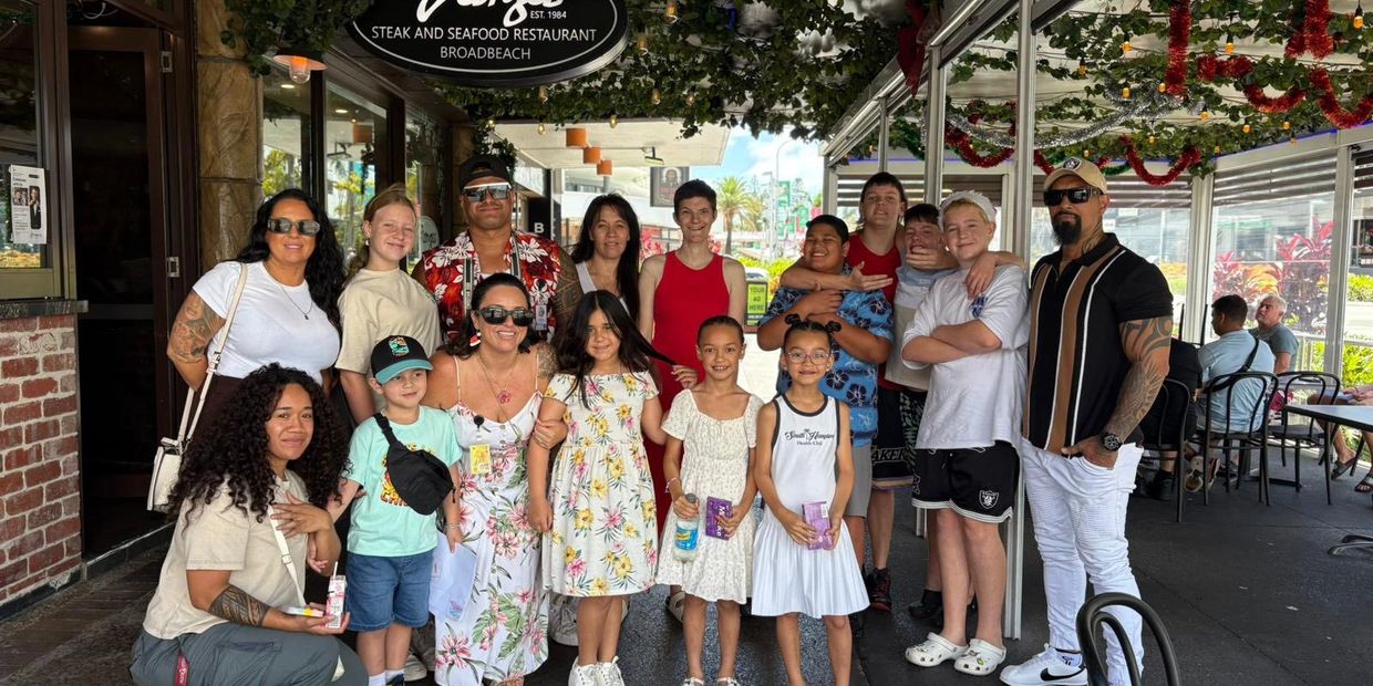 A diverse group of people posing outside a steak and seafood restaurant.