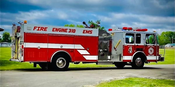 Red fire engine 318 EMS parked on a road under a cloudy sky.