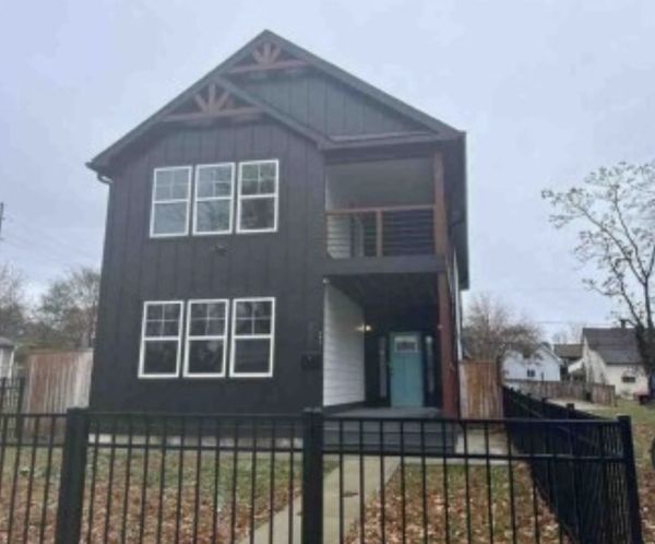 Modern black two-story house with gated yard.