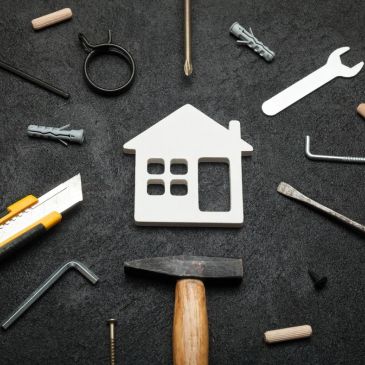 House model surrounded by tools on a black surface.