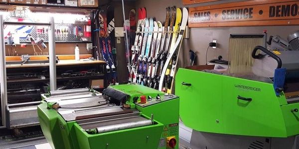Ski workshop with green tuning machines and racks of skis.