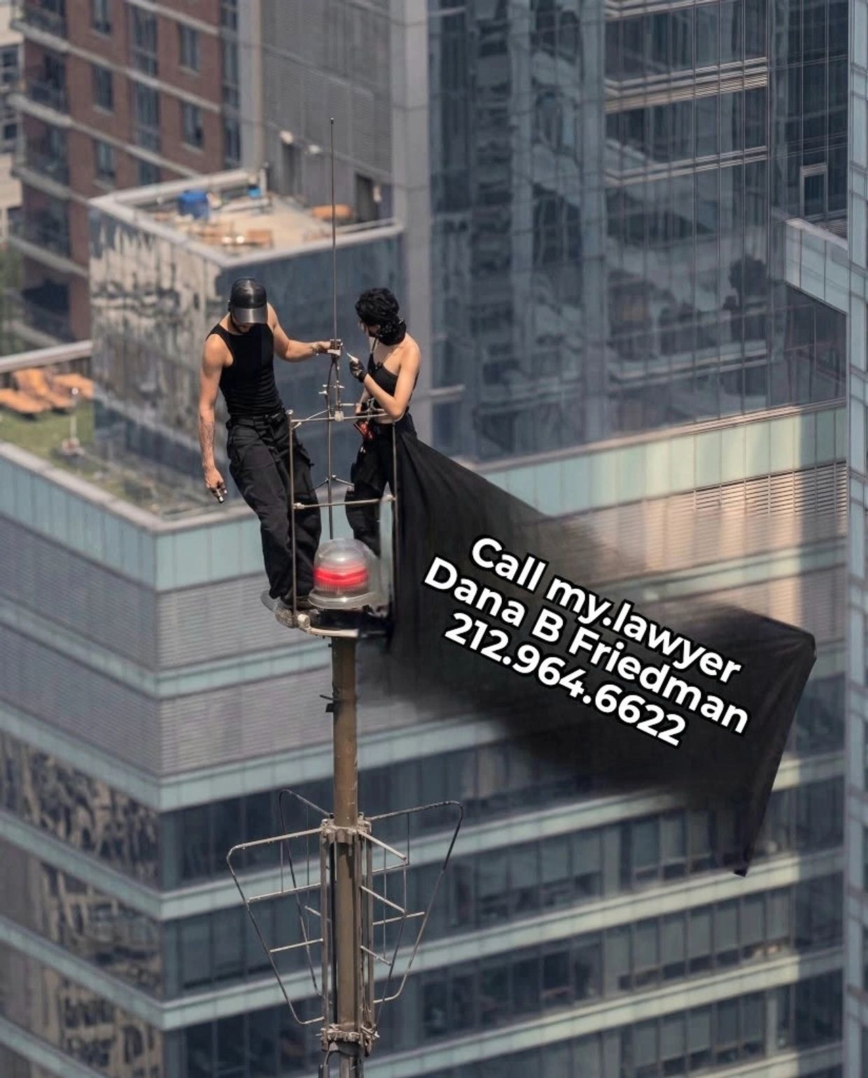 Two people standing on a building antenna with a legal advertisement.