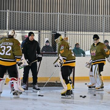 Ice hockey players practicing on an outdoor rink with coach guidance.