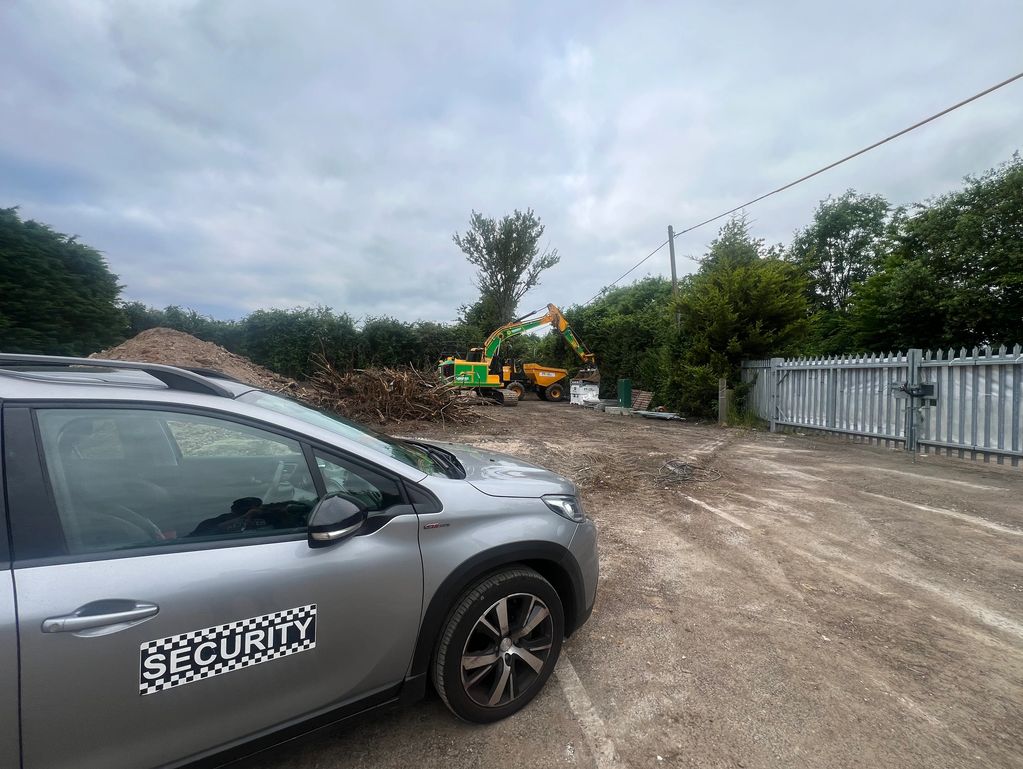 Security car parked near a construction site with machinery.