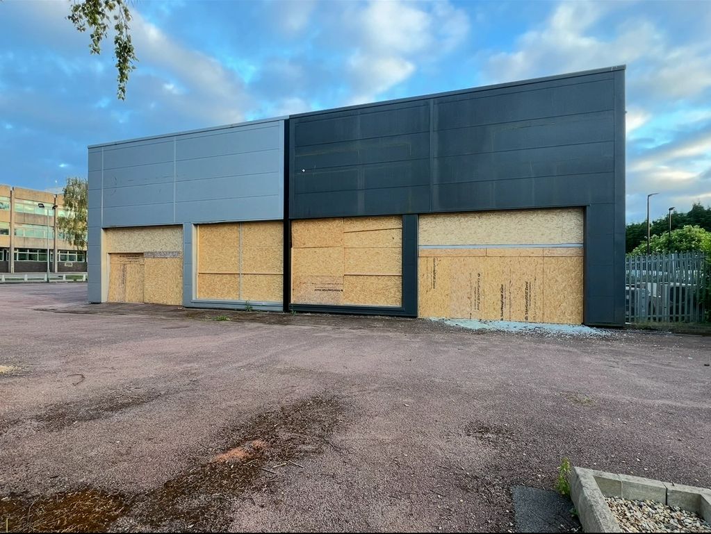 Boarded up modern industrial building under a blue sky.