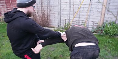 Two men practicing martial arts in a garden.