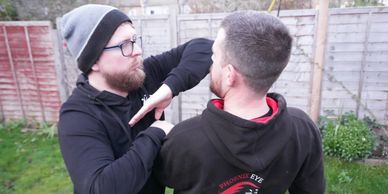 Two men practicing self-defense moves outdoors.
