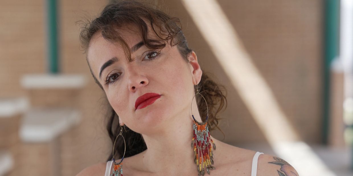 Close-up of a woman with bold red lipstick and colorful beaded earrings.