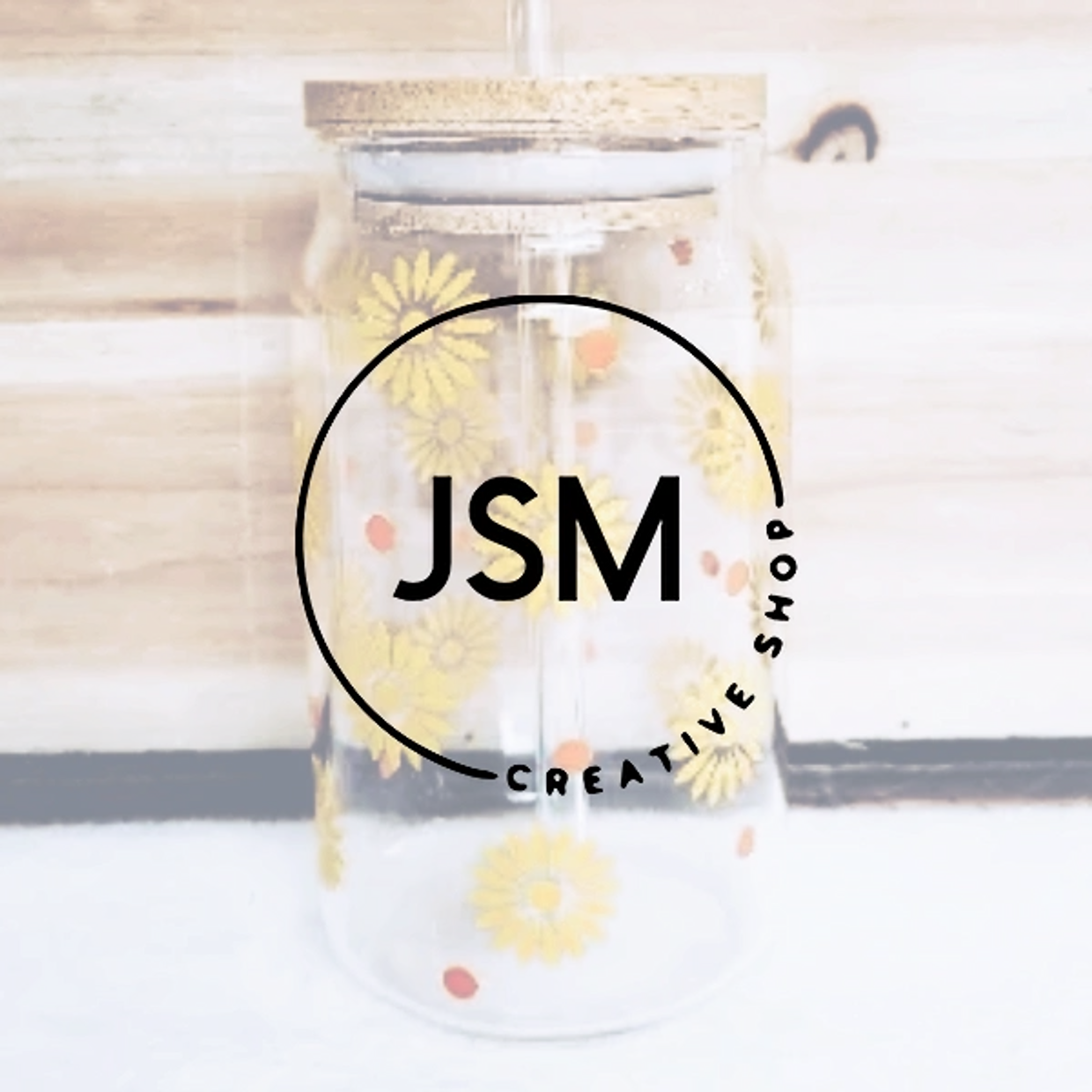 JSM logo for Creative shop with glass tumbler in the background. Designs with flowers