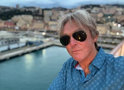 Man in sunglasses taking a selfie near a waterfront.
