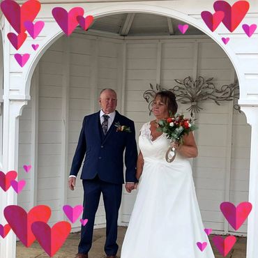 Couple in wedding attire holding hands under arch.