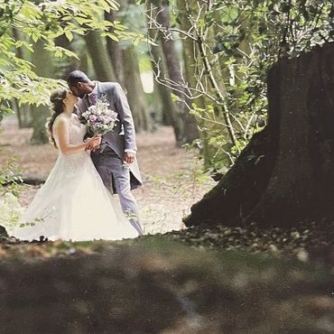 Bride and groom share a kiss in a forest.