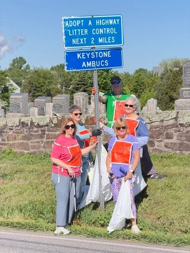 Group of adults wearing orange aprons posing outdoors near tombstones.