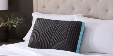 Black textured pillow on a white bed.