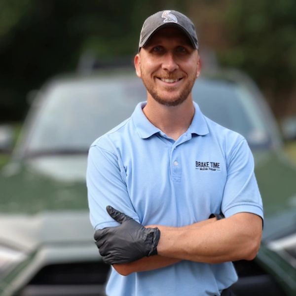 Man in a blue shirt and cap smiling with arms crossed.