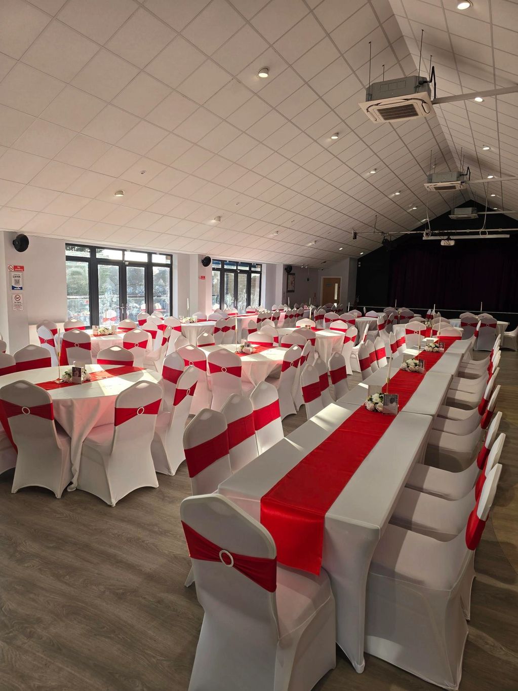 Event hall with white chairs and red sashes.