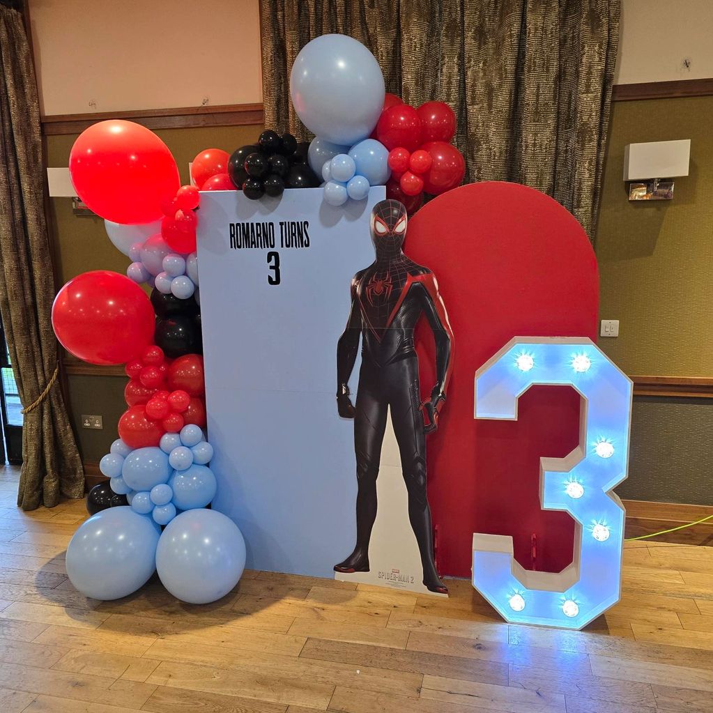 Spider-Man themed birthday setup with balloons and lights.