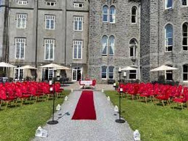 Outdoor wedding setup with red chairs and a red carpet aisle.